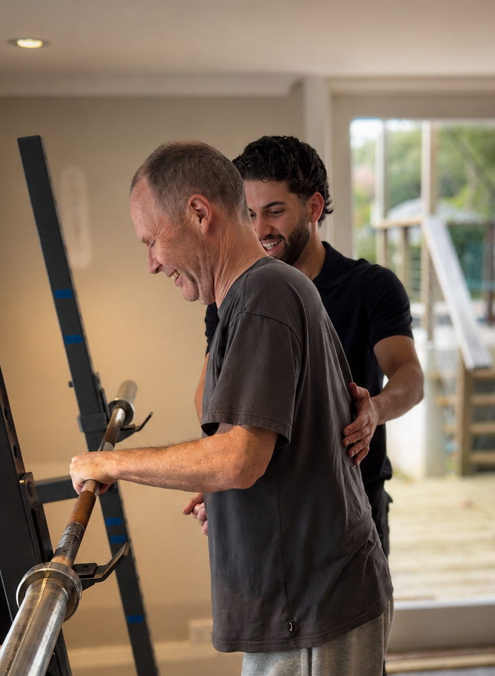 An Accredited Exercise Physiologist supporting a client through a squat rack exercise